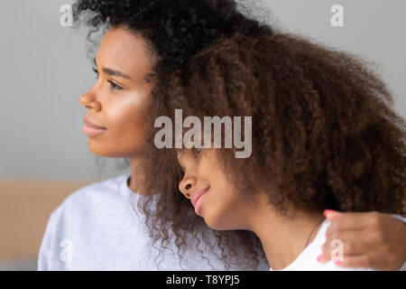 Close up giovane africana madre americana abbracciando la figlia teenager Foto Stock