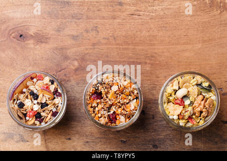 Assortimento di granola, muesli in vasetti di vetro. Una sana prima colazione. Avena con frutta, bacche e dadi. Vista dall'alto. Spazio di copia Foto Stock