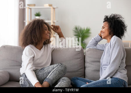 Felice African American madre e figlia teenager chat a home Foto Stock