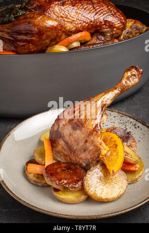 L Anatra arrosto gamba con patate, carote e arance Foto Stock