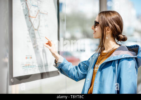 Donna che guarda sul regime del trasporto pubblico in piedi presso la stazione del tram e all'aperto Foto Stock