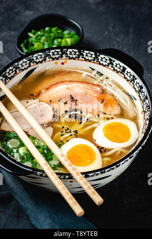 Giapponese Ramen zuppa di Udon Noodles, maiale, uova e lo scalogno in pietra scura sullo sfondo Foto Stock