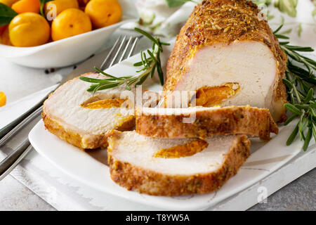 Rotolo di carne (involtino) con ripieno di albicocca e spezie su una luce di pietra o di sfondo di ardesia. La Giornata del ringraziamento antipasto. Foto Stock