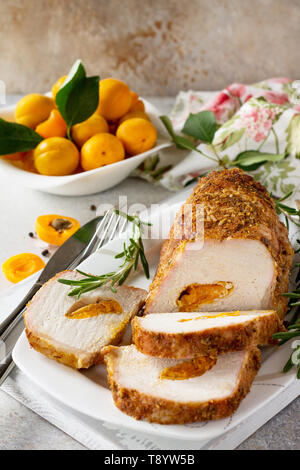 Rotolo di carne (involtino) con ripieno di albicocca e spezie su una luce di pietra o di sfondo di ardesia. La Giornata del ringraziamento antipasto. Copia dello spazio. Foto Stock