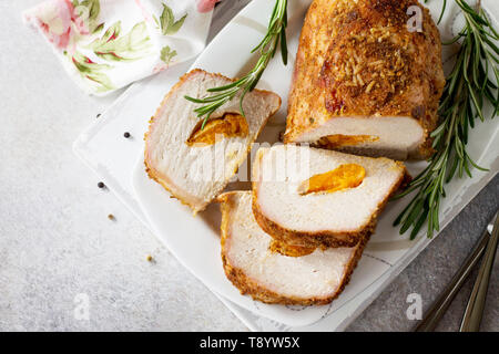 Rotolo di carne (involtino) con ripieno di albicocca e spezie su una luce di pietra o di sfondo di ardesia. La Giornata del ringraziamento antipasto. Vista superiore piatta backgrou laici Foto Stock