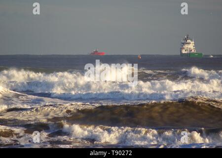 Le navi in servizio su una grossolana del Mare del Nord con onde che si infrangono sulla spiaggia di Aberdeen durante una tempesta di neve. La Scozia, Regno Unito. Foto Stock