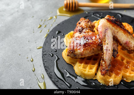 Deliziosi waffles con ali di pollo sulla piastra di ardesia Foto Stock