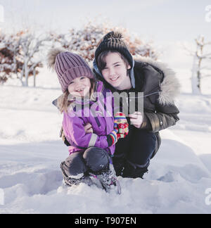 Due ragazze abbraccio e giocare nella neve Foto Stock