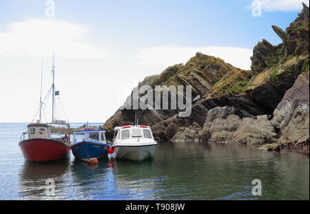 Il porto esterno di Polperro a bassa marea: tre barche da pesca ormeggiate al passo della roccia di picco Foto Stock