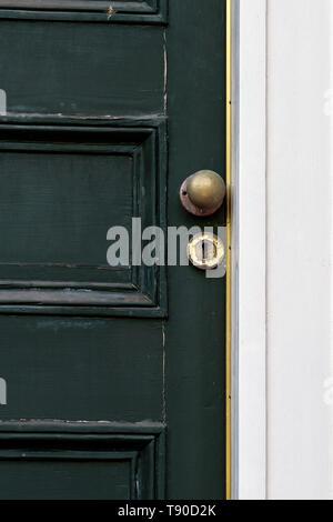 Antichi verde davanti la porta di casa vittoriana in stato di abbandono con peeling vernice e macchiata di ottone lion respingente, letter box, il pomello e il foro per la chiave. Foto Stock