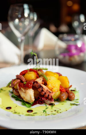 Polpo alla griglia, patate e verdura sulla tavola di ristorante Foto Stock