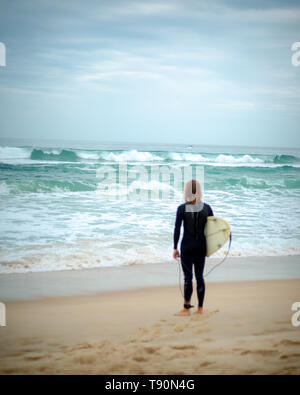 Surfer con la sensazione che il mare dalla sabbia, guardando le onde dalla spiaggia, aspettando il momento giusto, Florianopolis, Santa Catarina, Brasile. Foto Stock