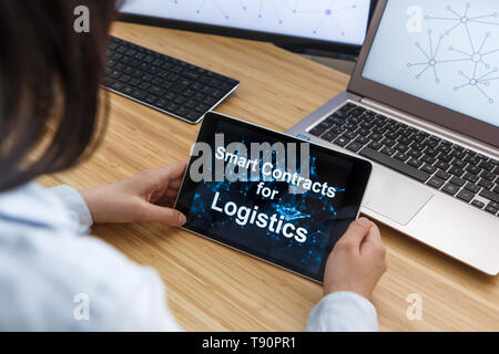 Femmina di business utilizzando Smart Contratti per la logistica. Illustrazione di Ethereum Blockchain sullo schermo del Tablet PC e laptop. Foto Stock