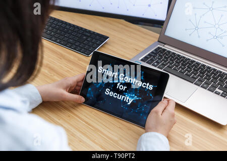 Femmina di business utilizzando Smart Contratti per la sicurezza. Illustrazione di Ethereum Blockchain sullo schermo del Tablet PC e laptop. Foto Stock