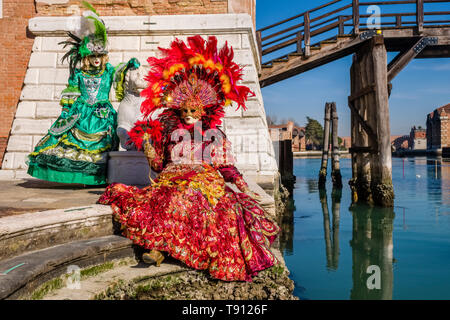 Due feminin persone mascherate in splendidi costumi creative, ponendo in edifici di Arsenale, celebra il Carnevale Veneziano Foto Stock