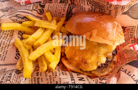 Cheeseburger e patatine fritte avvolti in un giornale Foto Stock