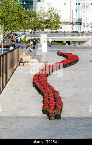 Un nastro di avvolgimento del rosso dei gerani nel recentemente completato il carbone scende cantiere, granaio Square in background, King's Cross, Londra, Regno Unito, 2019 Foto Stock