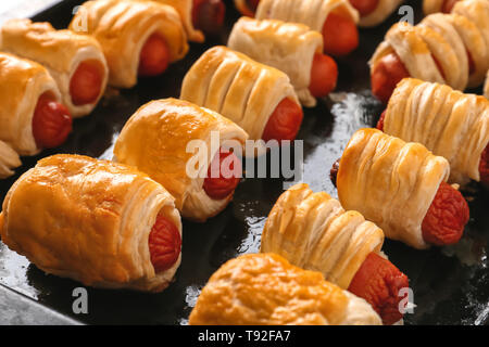 Fresco cotto al forno gustose salsicce rotoli su una teglia Foto Stock