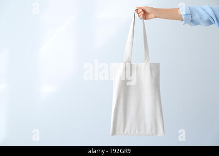 Mano femmina con eco bag su sfondo chiaro Foto Stock