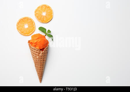 Cono di cialda con deliziosi gelati e fettine di arancio su sfondo bianco Foto Stock