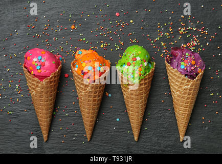 Coni di cialda con colori deliziosi gelati e spruzza su sfondo scuro Foto Stock
