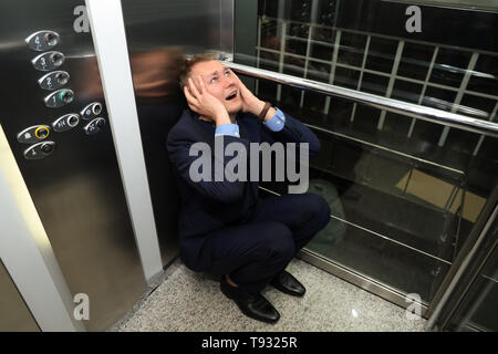 Imprenditore aventi attacco di panico in ascensore Foto Stock