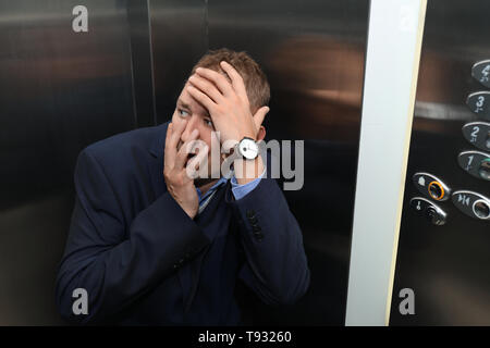 Imprenditore aventi attacco di panico in ascensore Foto Stock