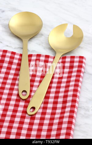 Alla moda e bellissimo golden cucchiaio e forchetta impostato in stile gingham placemat antichi e marmo di carrara Foto Stock