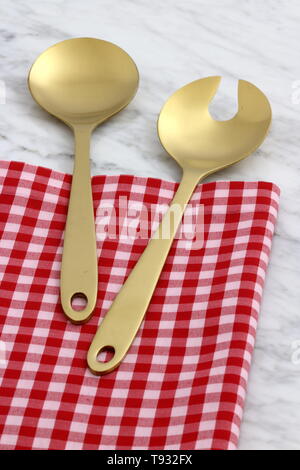 Alla moda e bellissimo golden cucchiaio e forchetta impostato in stile gingham placemat antichi e marmo di carrara Foto Stock