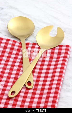 Alla moda e bellissimo golden cucchiaio e forchetta impostato in stile gingham placemat antichi e marmo di carrara Foto Stock