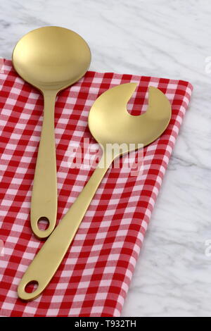 Alla moda e bellissimo golden cucchiaio e forchetta impostato in stile gingham placemat antichi e marmo di carrara Foto Stock