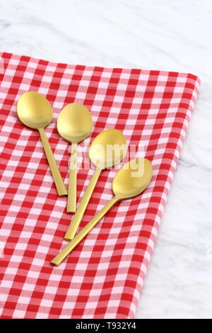 Alla moda e bellissimo golden cucchiaio e forchetta impostato in stile gingham placemat antichi e marmo di carrara Foto Stock