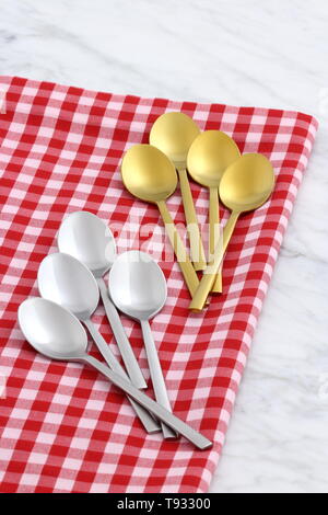 Alla moda e bellissimo golden cucchiaio e forchetta impostato in stile gingham placemat antichi e marmo di carrara Foto Stock