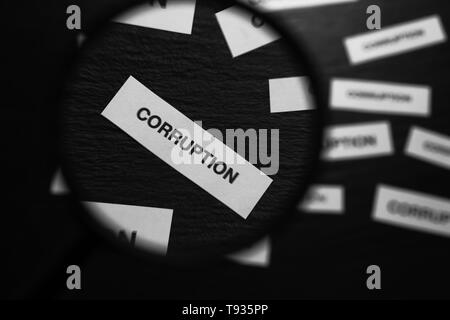 Vista sul pezzo di carta con la parola corruzione attraverso la lente di ingrandimento di vetro su sfondo nero Foto Stock