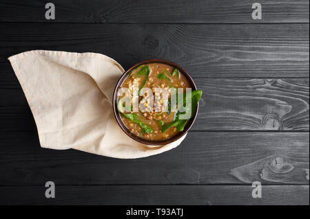 Mung Dhal con spinaci verde al nero da tavolo in legno. Moong Dal - Cucina Indiana curry. Piatto vegetariano con zira e coriandolo .vista dall'alto uno spazio di copia Foto Stock