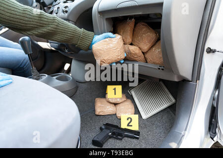 Poliziotto holding pacchetto farmaco scoperto nel compartimento segreto in un auto Foto Stock