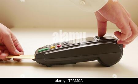 Lo sfioramento a mano carta di credito nel negozio. Mani femminili con carta di credito e bonifico terminale. Immagine a colori di un POS e carte di credito Foto Stock