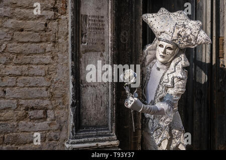 Ritratto di un masculin mascherata persona in uno splendido costume creativa, che pongono di fronte a un malato la parete in mattoni, celebra il Carnevale Veneziano Foto Stock