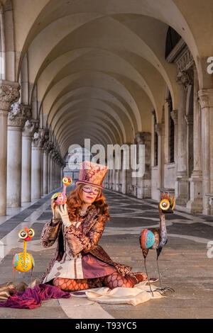 Una donna mascherata in un bellissimo costume di creative, ponendo sotto i portici di Palazzo Ducale, Palazzo Ducale, celebra il Carnevale Veneziano Foto Stock