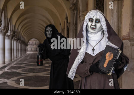 Ritratti di una coppia mascherata in spaventoso costumi creative, ponendo sotto i portici di Palazzo Ducale, Palazzo Ducale, celebra il Carnevale Veneziano Foto Stock