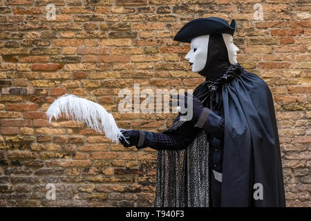 Ritratto di un masculin mascherata persona in uno splendido costume creativa, che pongono di fronte a un malato la parete in mattoni, celebra il Carnevale Veneziano Foto Stock