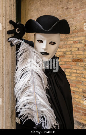 Ritratto di un masculin mascherata persona in uno splendido costume creativa, che pongono di fronte a un muro di mattoni, celebra il Carnevale Veneziano Foto Stock