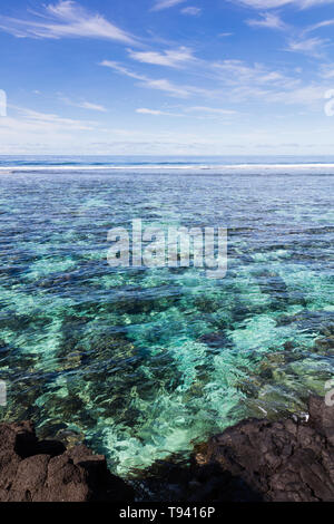 Il chiaro blu oceano pacifico acqua nera con pietre vulcaniche nella barriera corallina su un isola tropicale, Samoa, Polinesia. Foto Stock