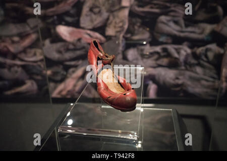 Una donna vestito della scarpa è di fronte a un enorme foto di scarpe scartati nel museo del patrimonio ebraico "Auschwitz. Non molto tempo fa. Non lontano dall' esposizione. Foto Stock