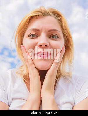 Donna sorridente bracci sollevati fino a testa, sul cielo blu. Foto Stock