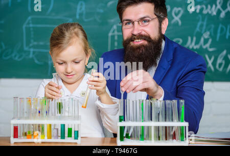 Spiegare la chimica a kid. Come interesse lo studio di bambini. Affascinante lezione di chimica. Uomo Barbuto maestro e allievo con provette in aula. Lezione privata. Scuola di esperimento di chimica. Foto Stock