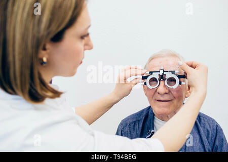 All'ottico optometrista rendendo un occhio il test a un senior man.minorazione visiva persone di età Foto Stock