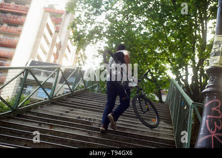 Un uomo che porta la sua bicicletta attraverso un ponte nel centro della città di Parigi Foto Stock