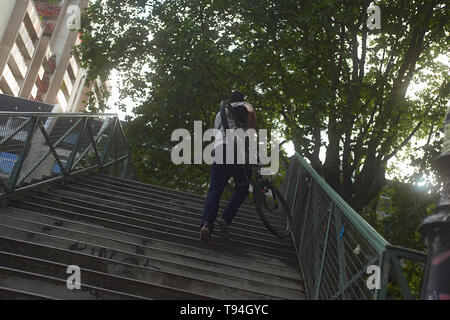 Un uomo che porta la sua bicicletta attraverso un ponte nel centro della città di Parigi Foto Stock