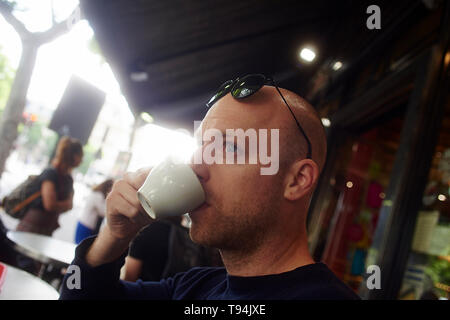 Elegante uomo caucasico seduto su una terrazza nel centro della città di Parigi godendo il suo caffè del mattino Foto Stock